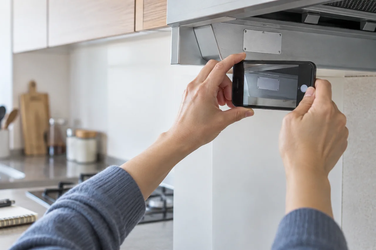 住宅設備の表示板をスマートフォンで撮影する手元